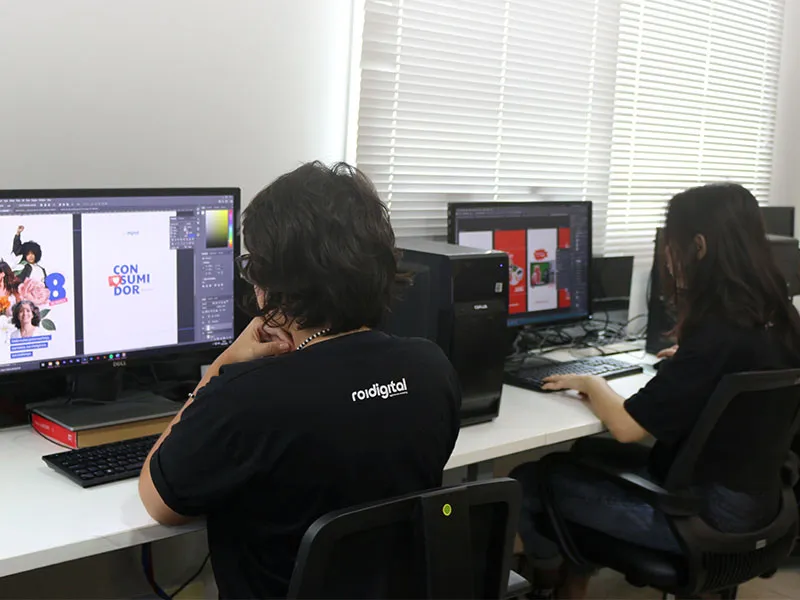 Designers da ROI Digital trabalhando em peças criativas nos monitores