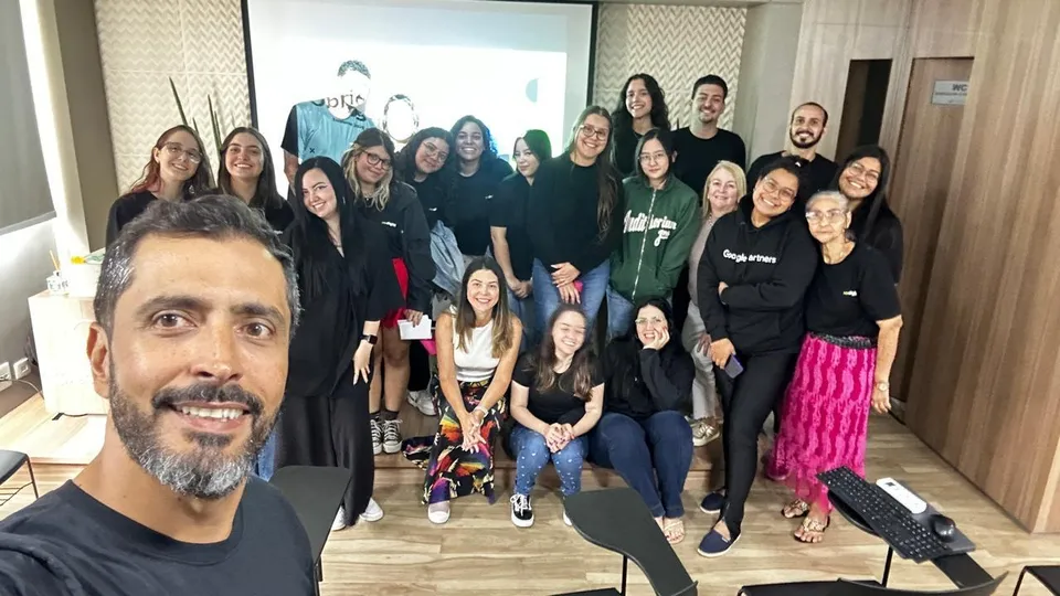 Selfie do fundador ao lado de parte da equipe da ROI Digital reunida em uma sala